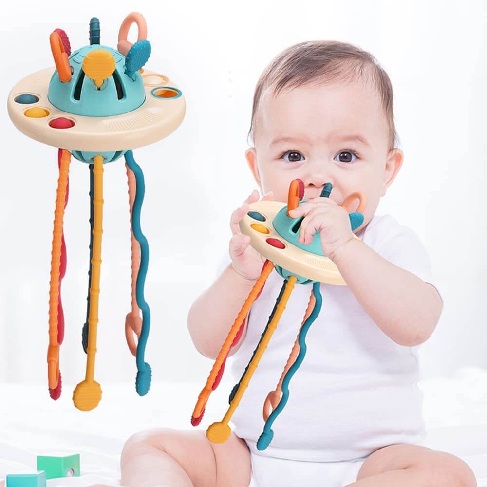 Glad baby som leker med en fargerik silikon UFO-trekkleke, utvikler gripeferdigheter.
