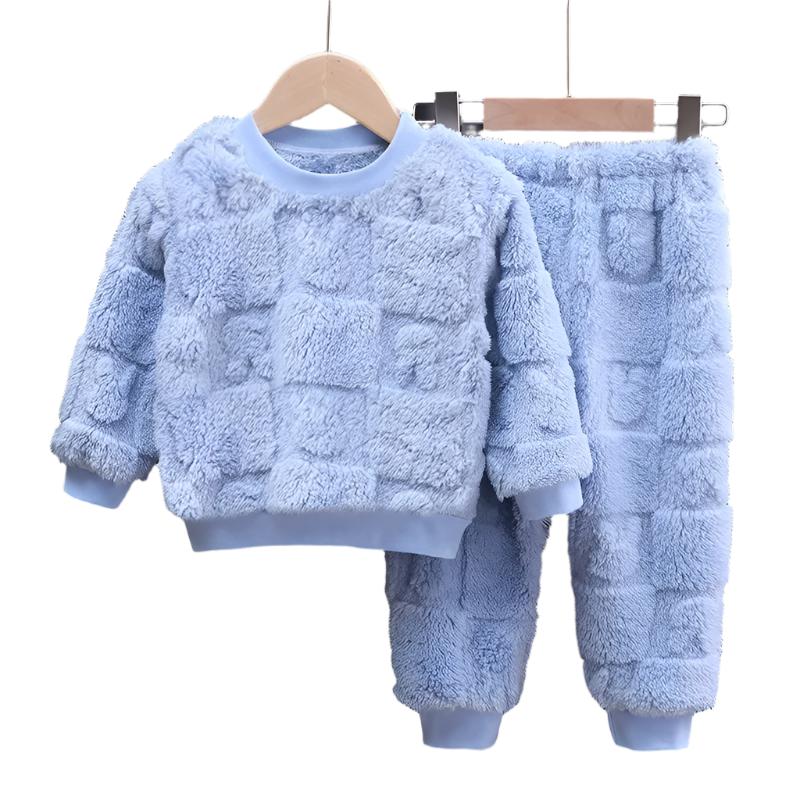 Barnepyjamas i flanell, designet for vinterbruk, ligger brettet og klar på en seng.