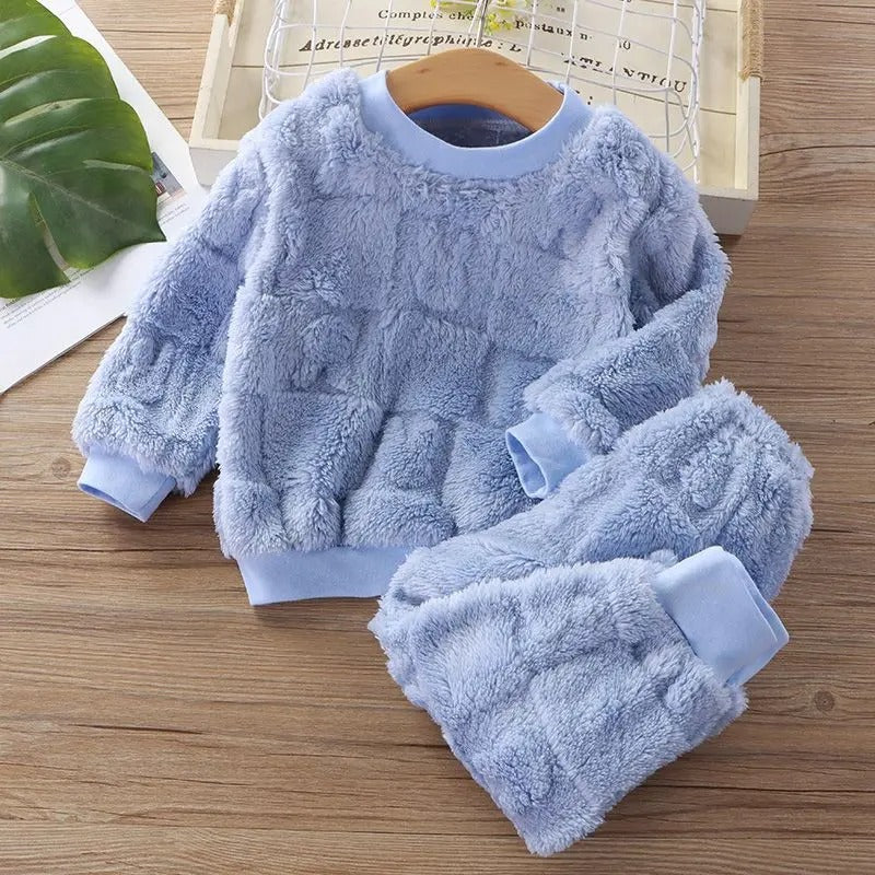 To barn, en jente og en gutt, ler sammen i matchende, varme flanellpyjamaser.