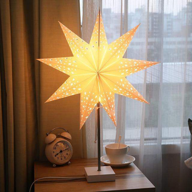 Hvit papir bordlampe formet som en stjerne, gir varmt og innbydende stemningslys.