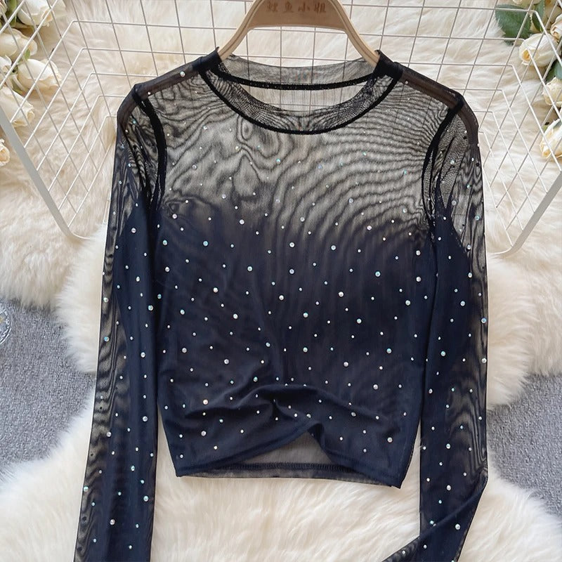 Detaljer av glitrende crop topp med forseggjorte rhinestones på lange ermer, festmote.