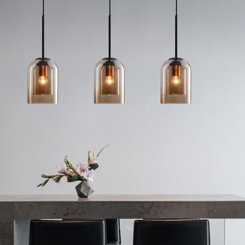 To stilige røykgrå glasskjermer på denne dobbel pendellampen, perfekt for moderne stuebelysning.