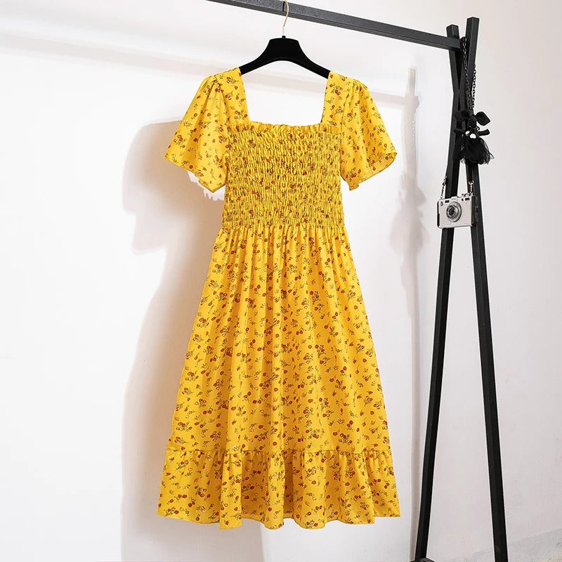 Feminin midikjole med blomstertrykk og plissering, en elegant ryggløs kvinnekjole for sommer og fest.