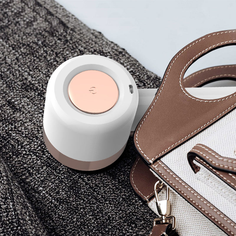 Elegant hvit nuppefjerner i ABS/PC og stål for skånsom oppfriskning av klær. Ergonomisk og trådløs med sikkerhetsmekanisme.