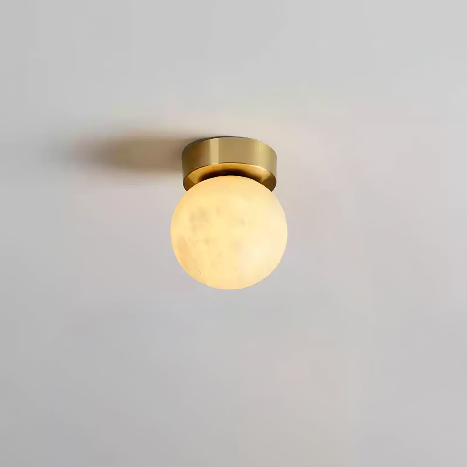 "Elegant Moon Alabaster taklampe i messing og alabast, med mykt, varmt lys for en innbydende atmosfære."