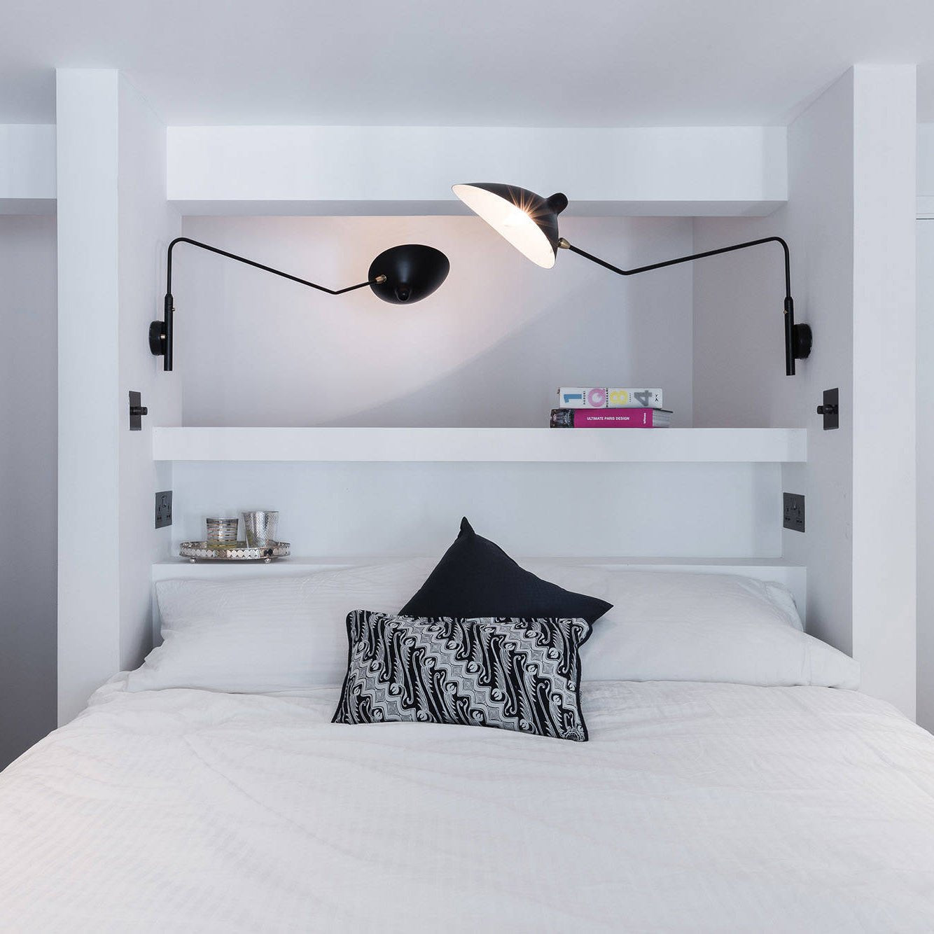 "Elegant Serge Mouille vegglampe med justerbar arm, insektlignende design, passer moderne innredning i svart eller hvit."