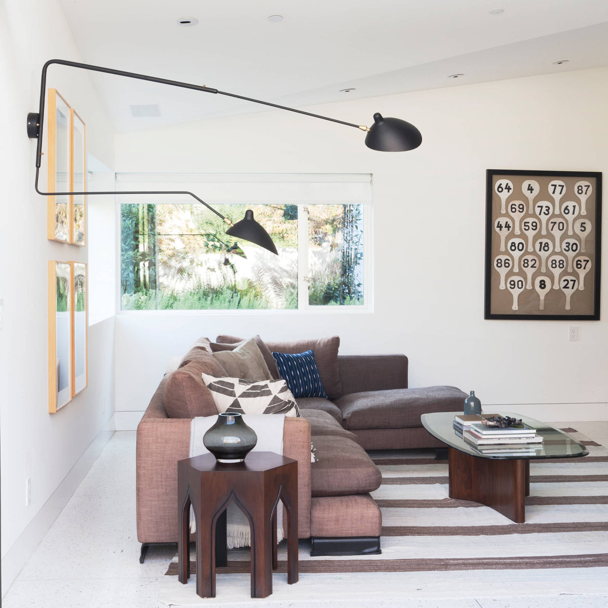 "Elegant Serge Mouille vegglampe med justerbar arm, insektlignende design, passer moderne innredning i svart eller hvit."
