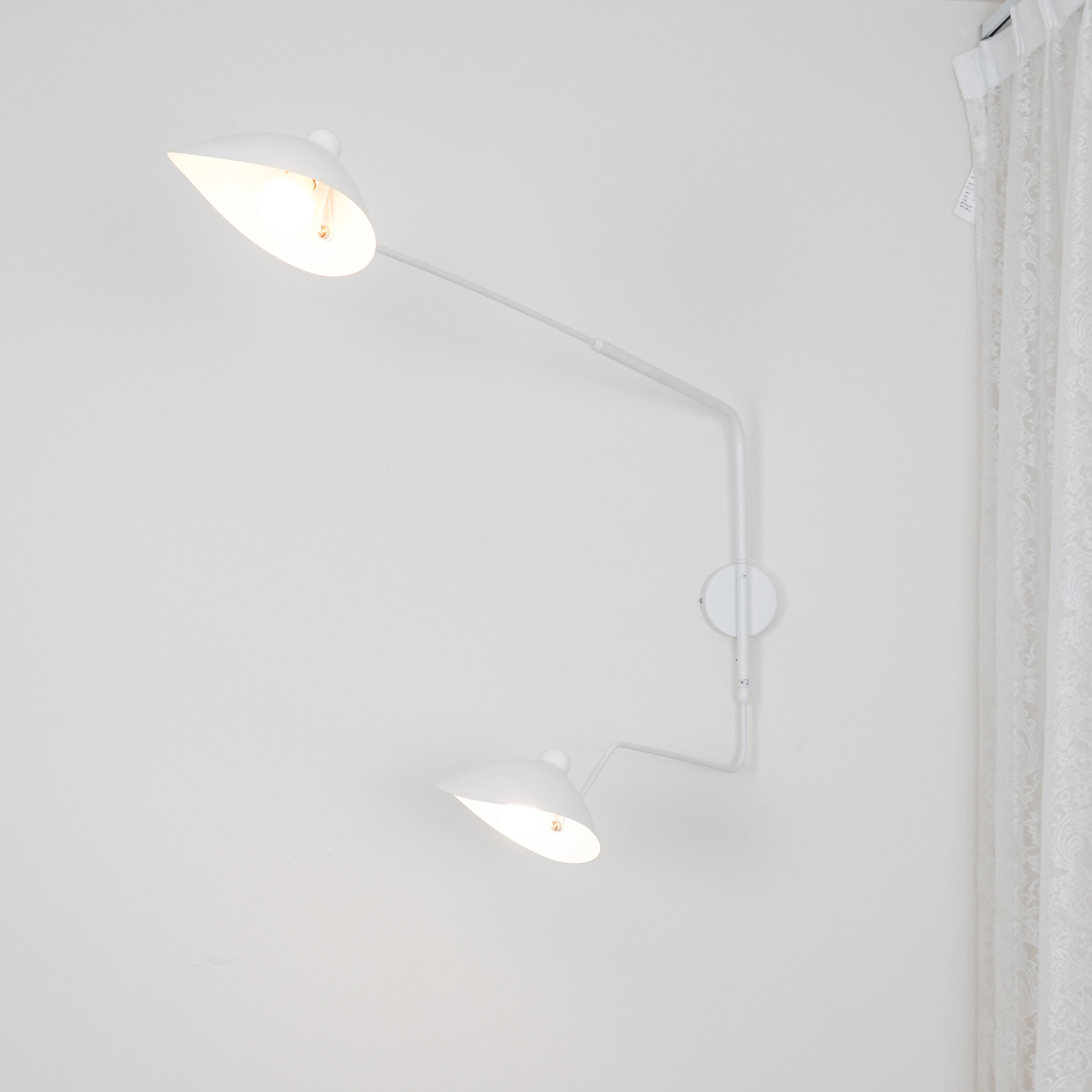 "Elegant Serge Mouille vegglampe med justerbar arm, insektlignende design, passer moderne innredning i svart eller hvit."