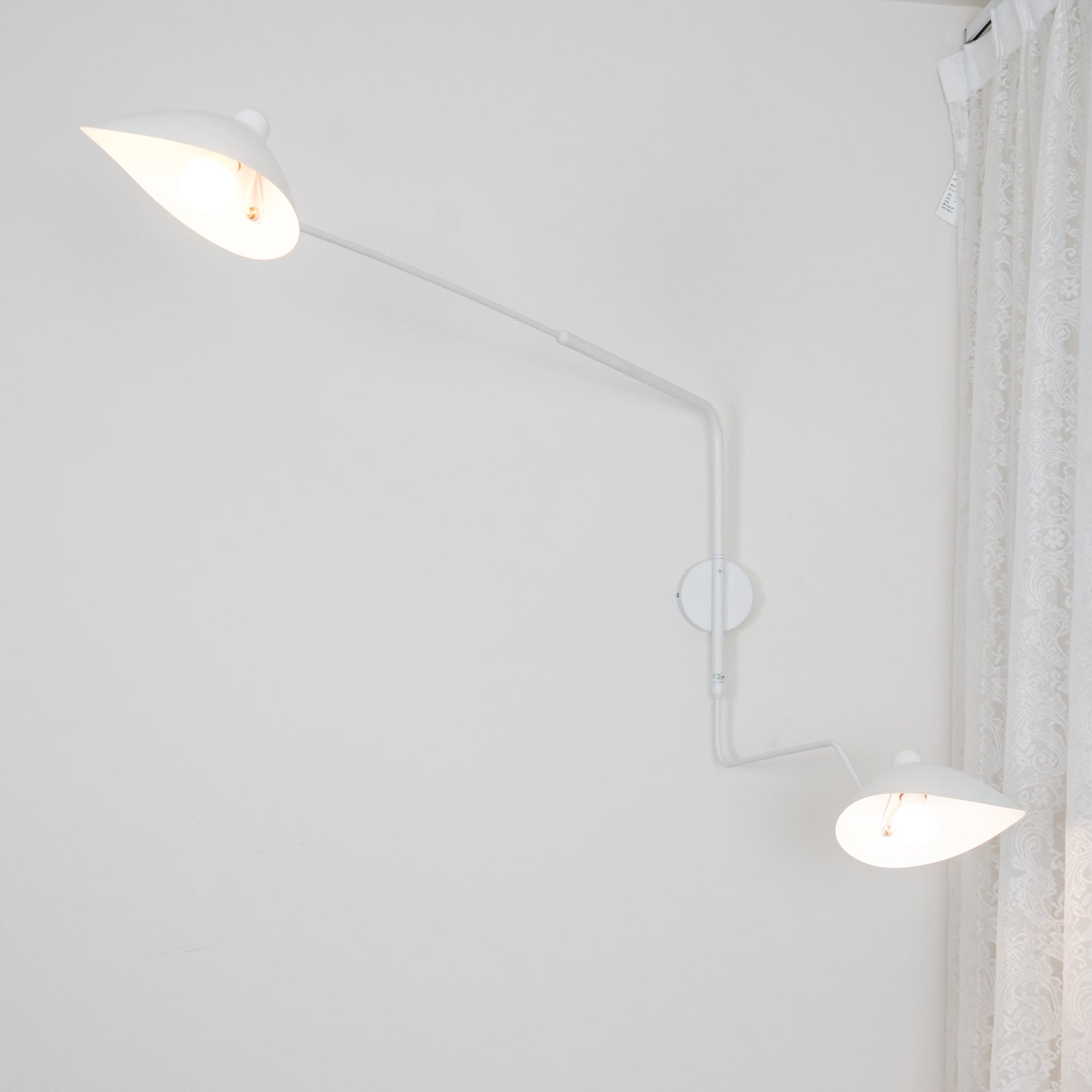 "Elegant Serge Mouille vegglampe med justerbar arm, insektlignende design, passer moderne innredning i svart eller hvit."