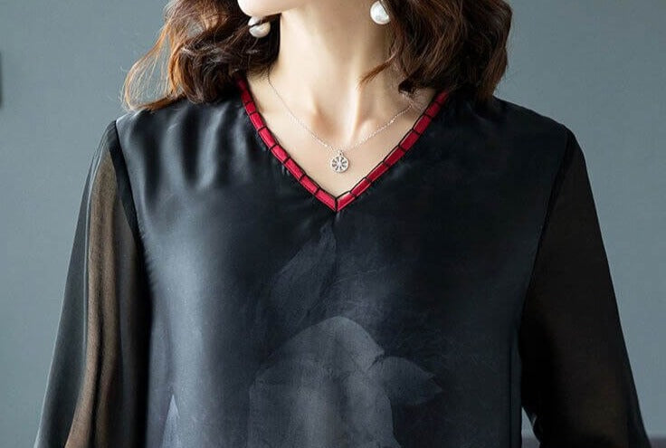 Nærbilde av falden på en elegant sort damekjole i silke, som viser midi-lengden og det flytende stoffet.