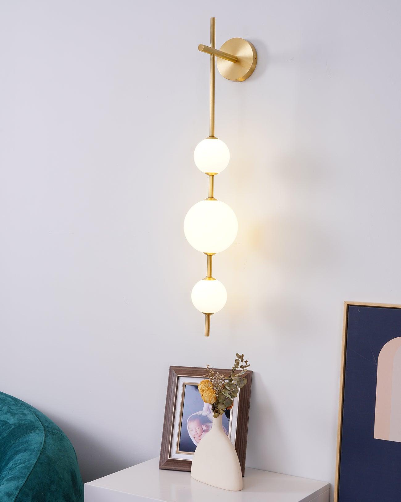 "Elegant vegglampe i glass og messing med kuleformede skjermer for mykt lys, perfekt for moderne og klassiske hjem."