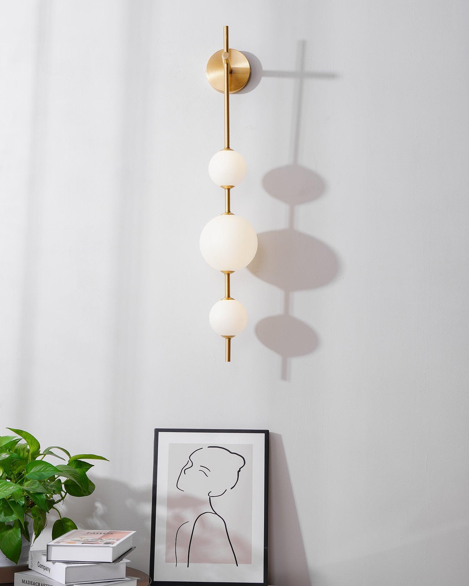 "Elegant vegglampe i glass og messing med kuleformede skjermer for mykt lys, perfekt for moderne og klassiske hjem."