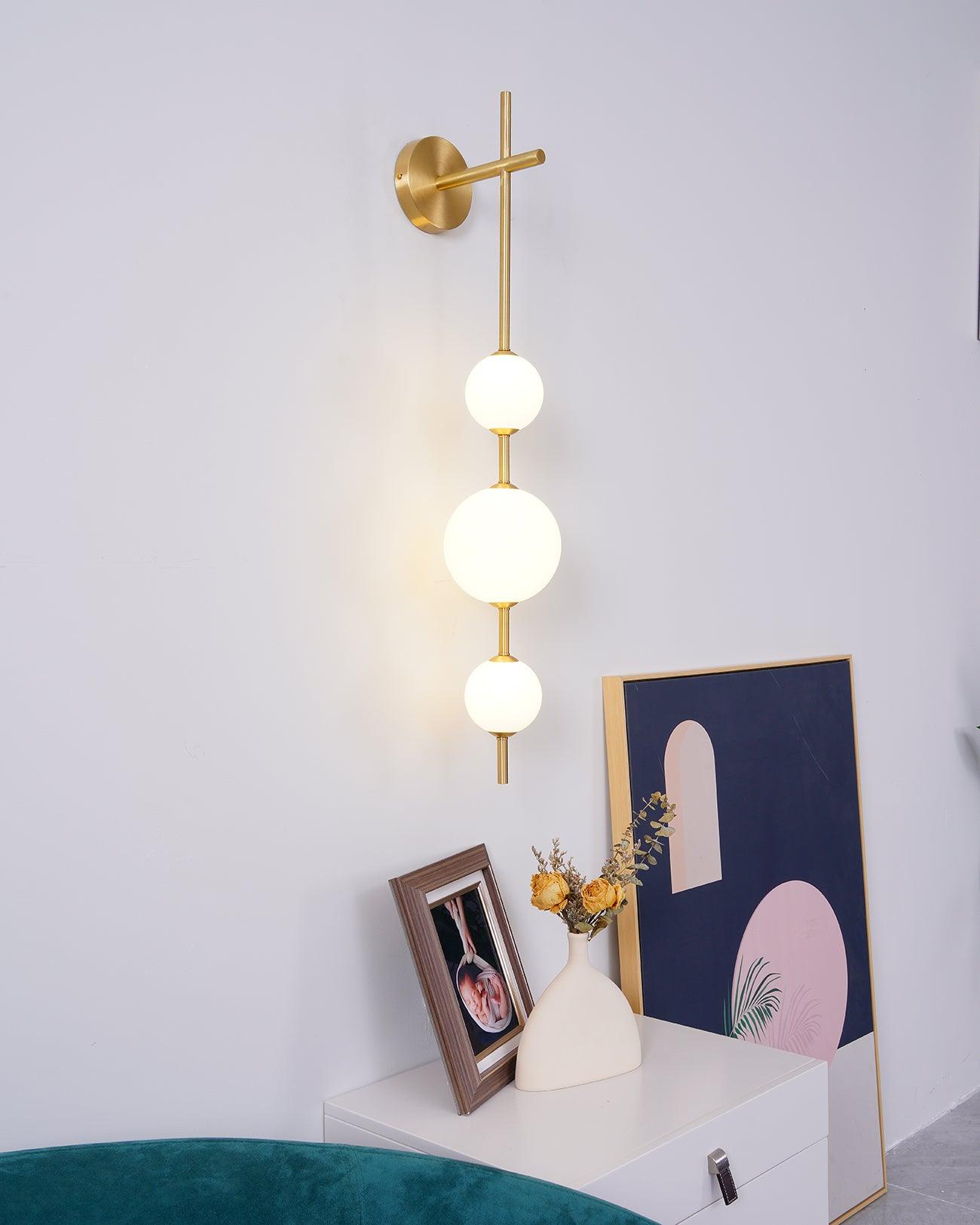"Elegant vegglampe i glass og messing med kuleformede skjermer for mykt lys, perfekt for moderne og klassiske hjem."
