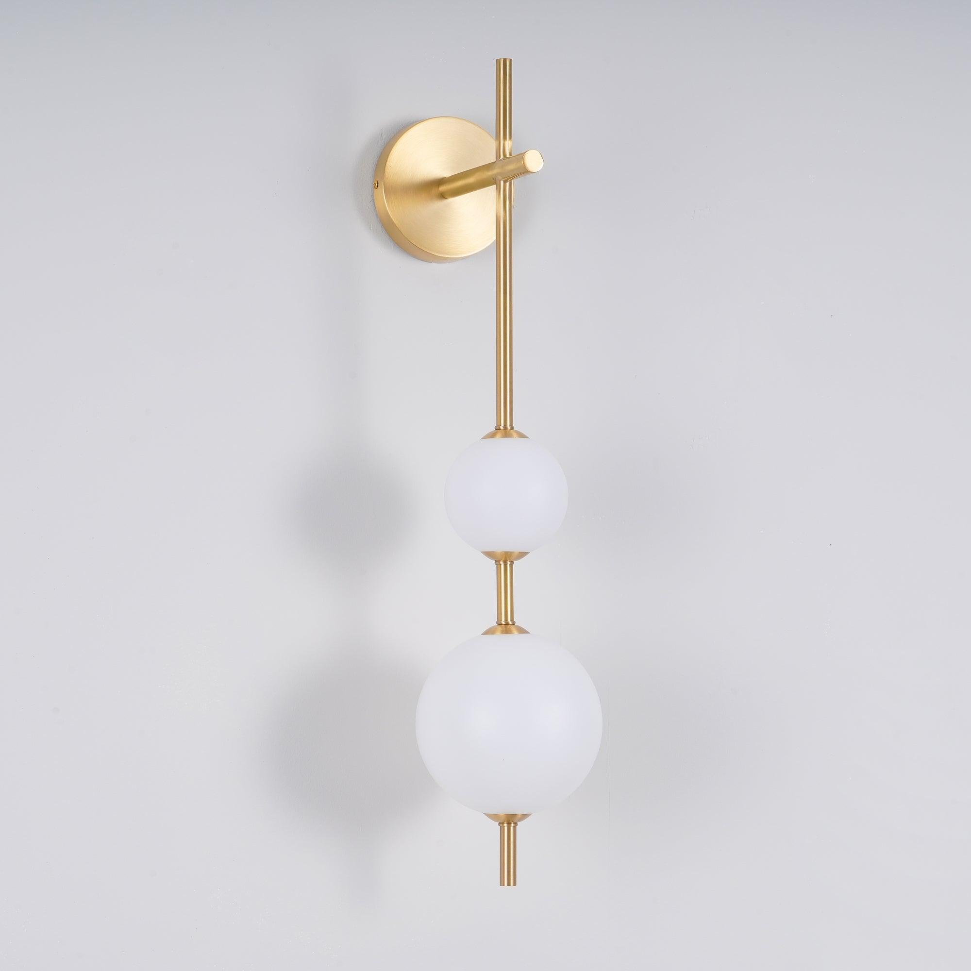 "Elegant vegglampe i glass og messing med kuleformede skjermer for mykt lys, perfekt for moderne og klassiske hjem."