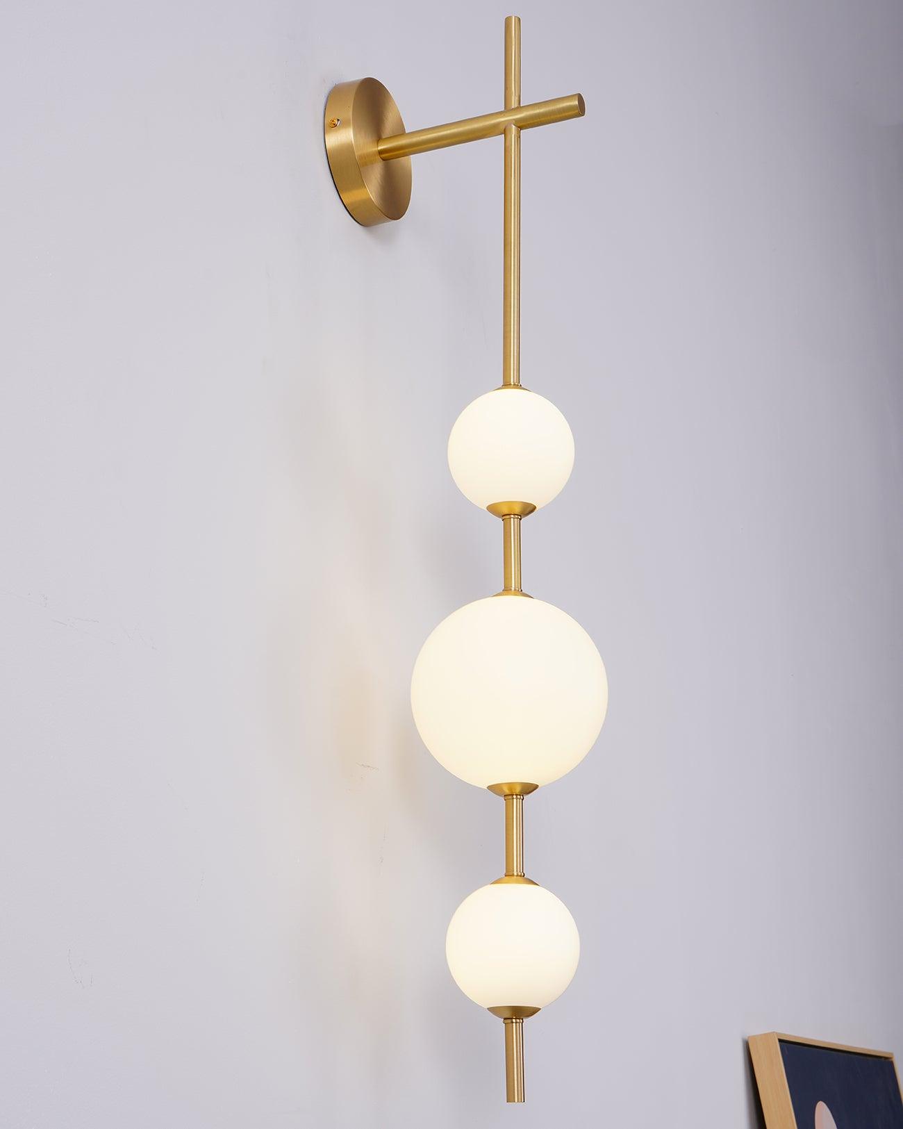 "Elegant vegglampe i glass og messing med kuleformede skjermer for mykt lys, perfekt for moderne og klassiske hjem."