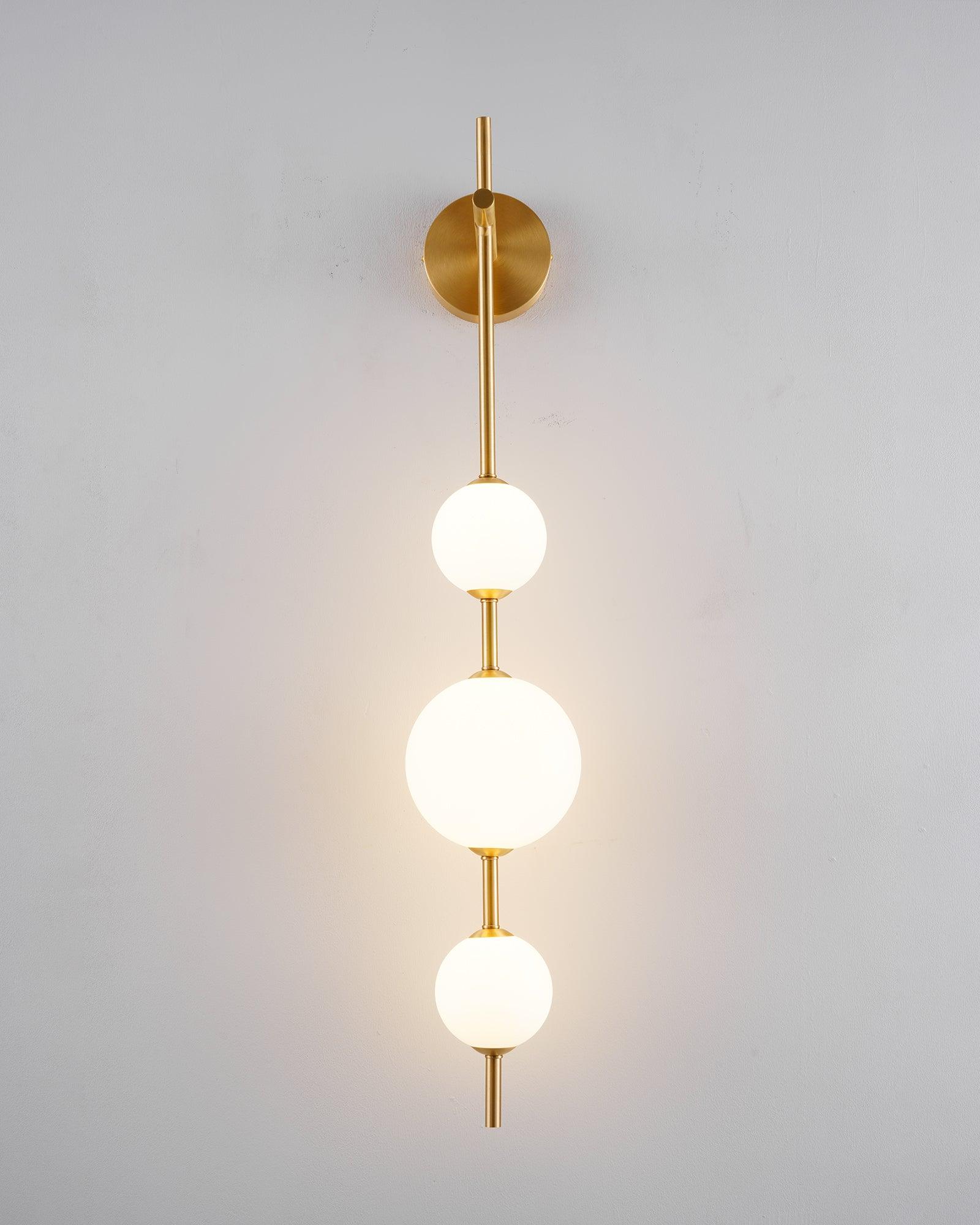 "Elegant vegglampe i glass og messing med kuleformede skjermer for mykt lys, perfekt for moderne og klassiske hjem."