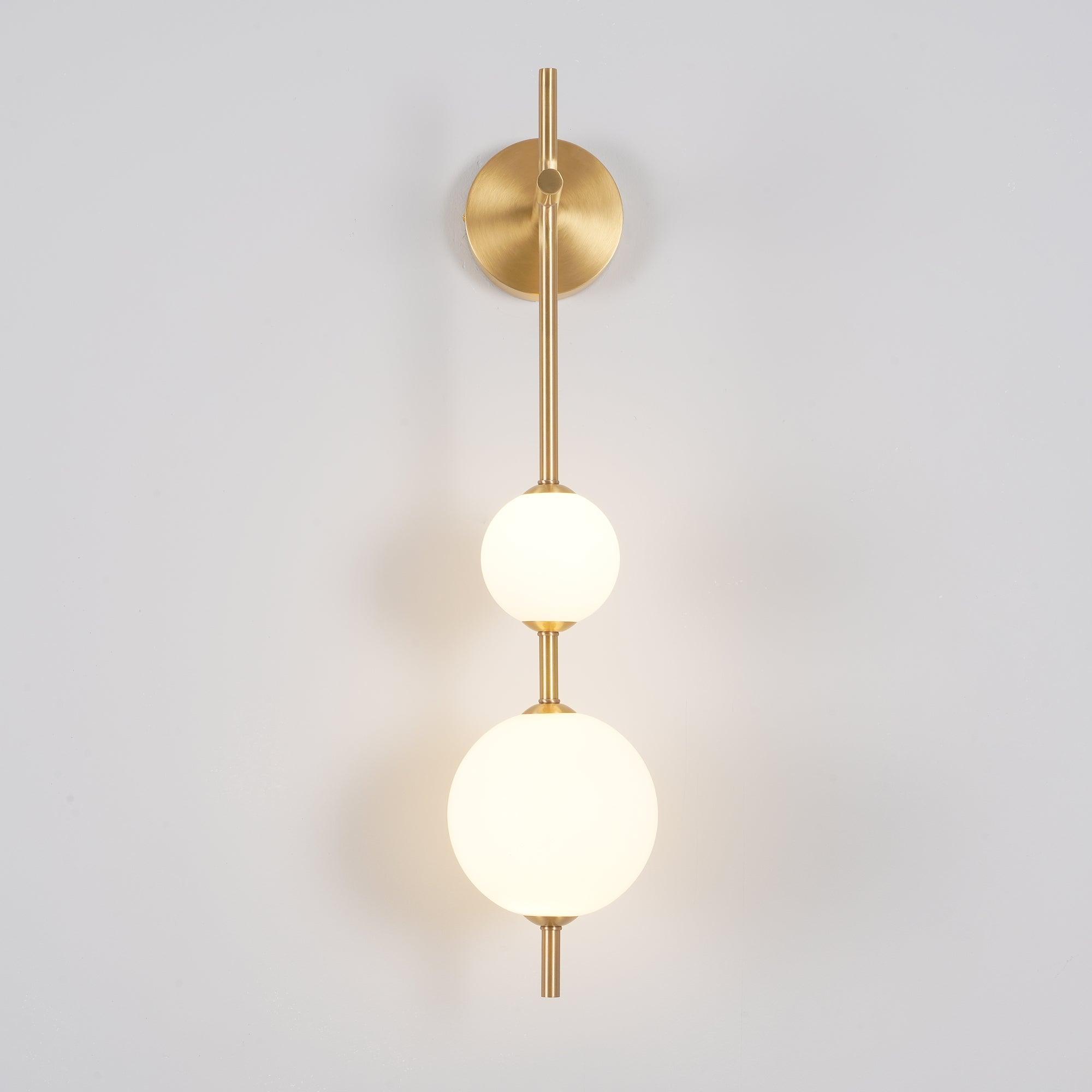 "Elegant vegglampe i glass og messing med kuleformede skjermer for mykt lys, perfekt for moderne og klassiske hjem."