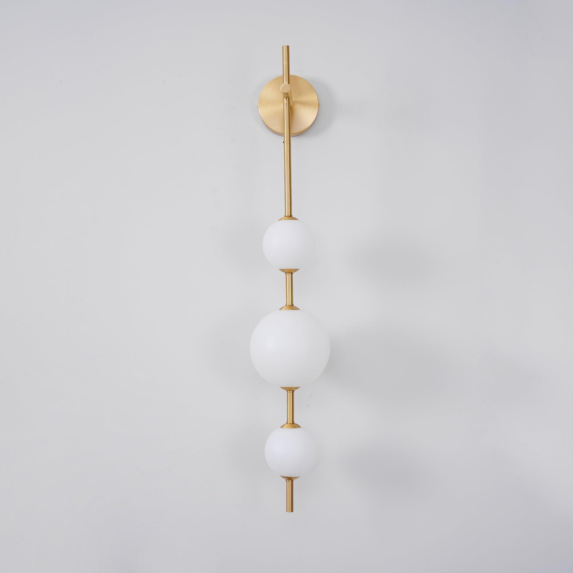 "Elegant vegglampe i glass og messing med kuleformede skjermer for mykt lys, perfekt for moderne og klassiske hjem."