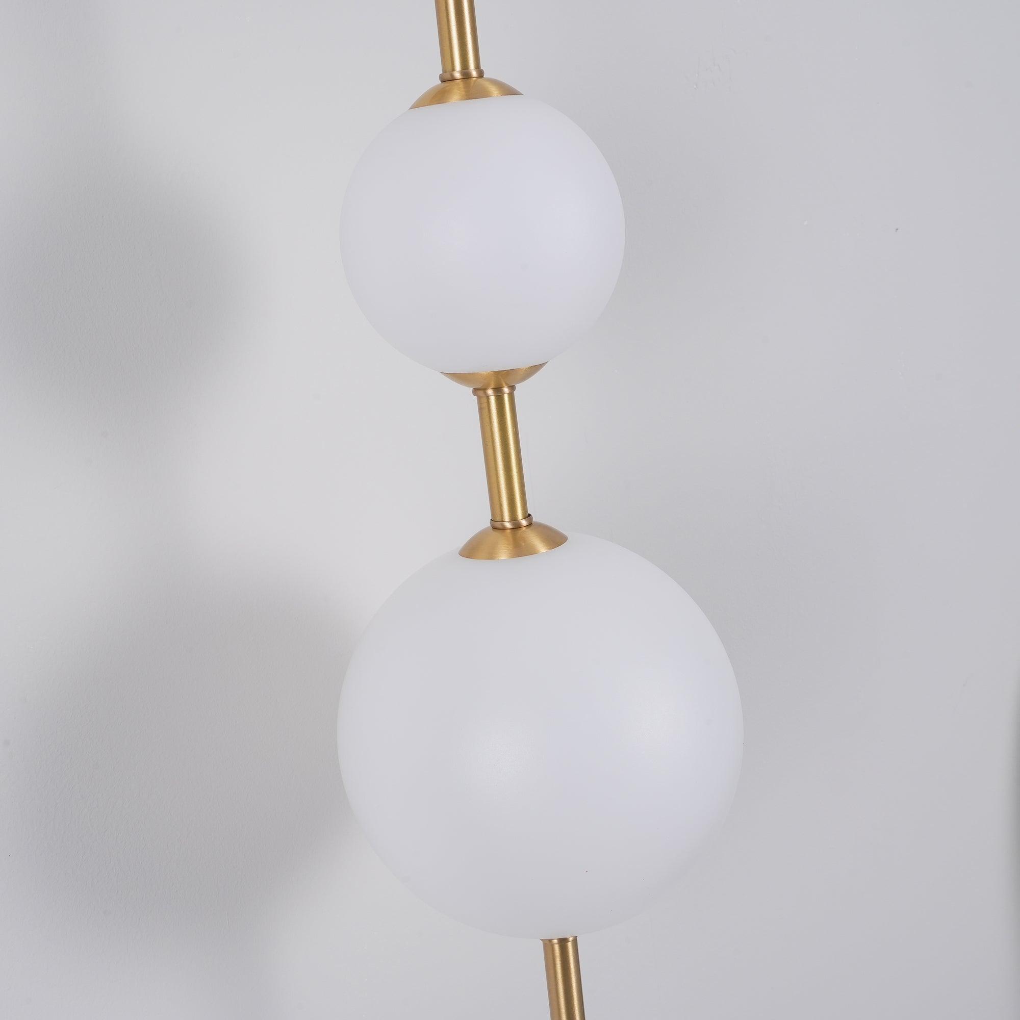 "Elegant vegglampe i glass og messing med kuleformede skjermer for mykt lys, perfekt for moderne og klassiske hjem."