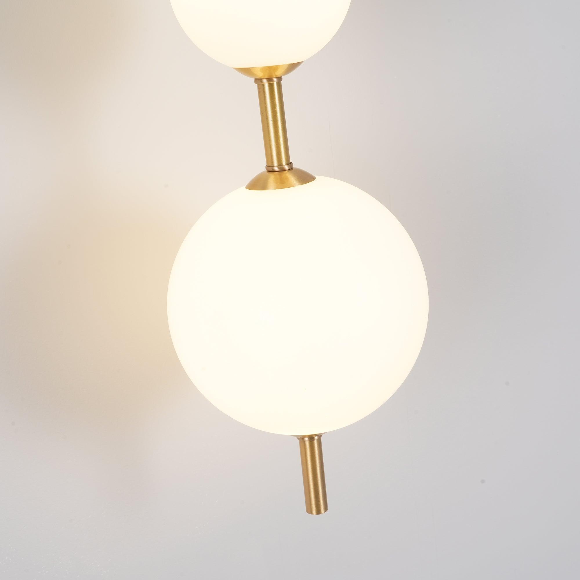 "Elegant vegglampe i glass og messing med kuleformede skjermer for mykt lys, perfekt for moderne og klassiske hjem."