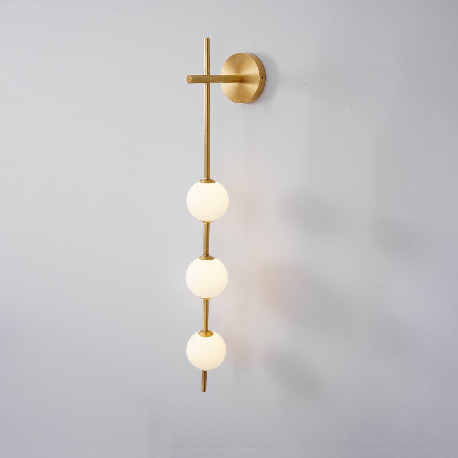 "Elegant vegglampe i glass og messing med kuleformede skjermer for mykt lys, perfekt for moderne og klassiske hjem."