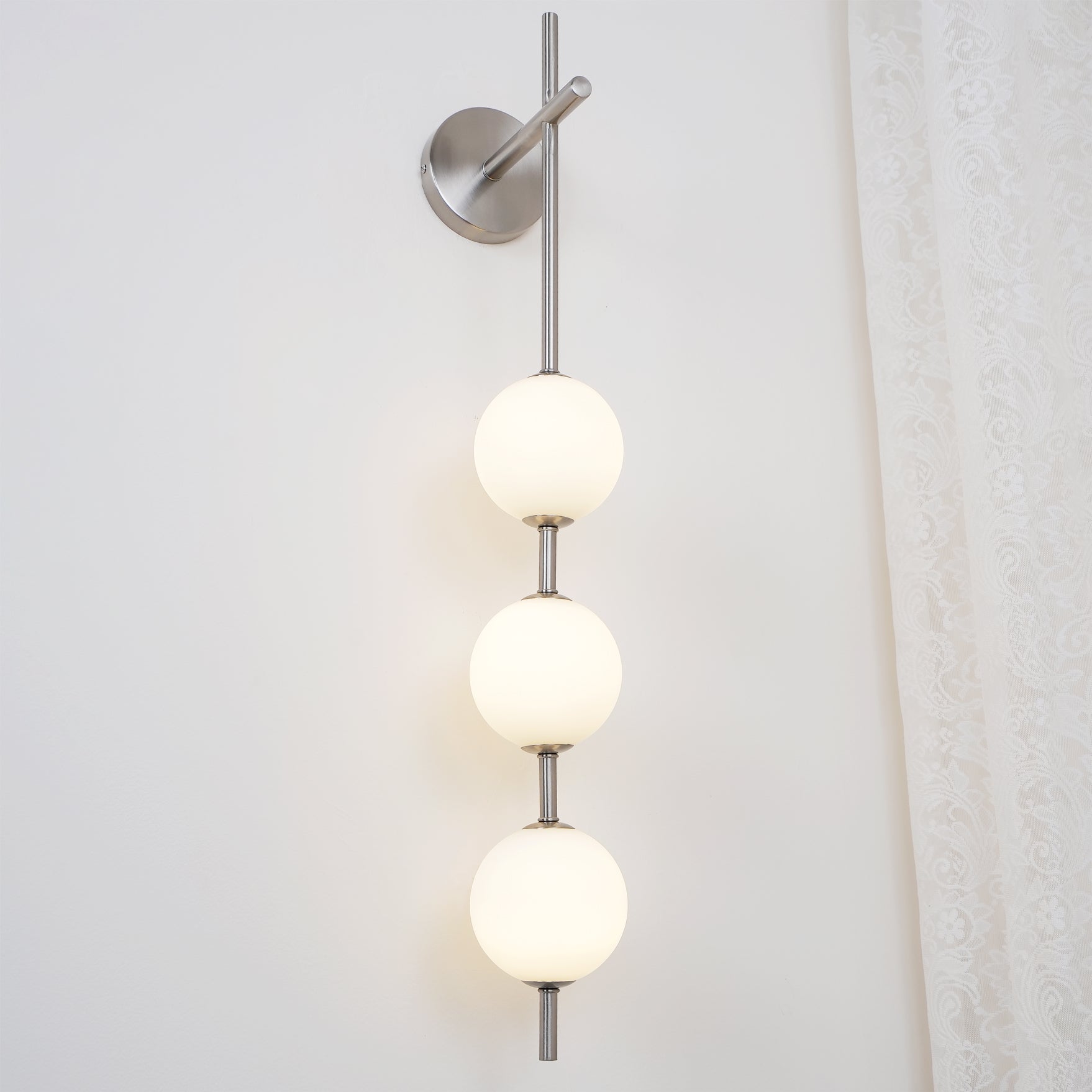 "Elegant vegglampe i glass og messing med kuleformede skjermer for mykt lys, perfekt for moderne og klassiske hjem."