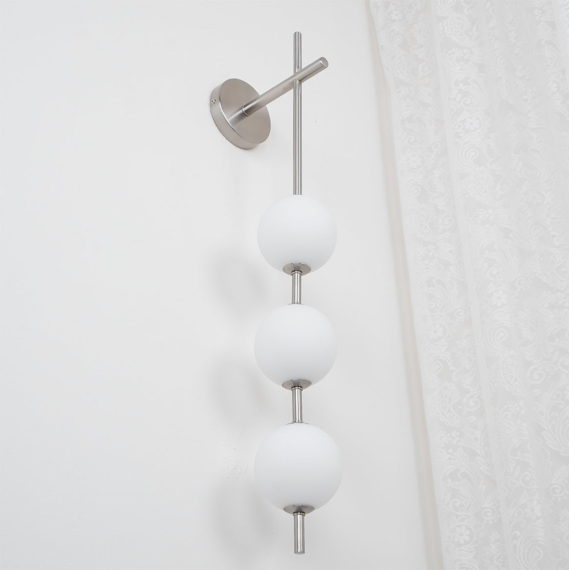 "Elegant vegglampe i glass og messing med kuleformede skjermer for mykt lys, perfekt for moderne og klassiske hjem."