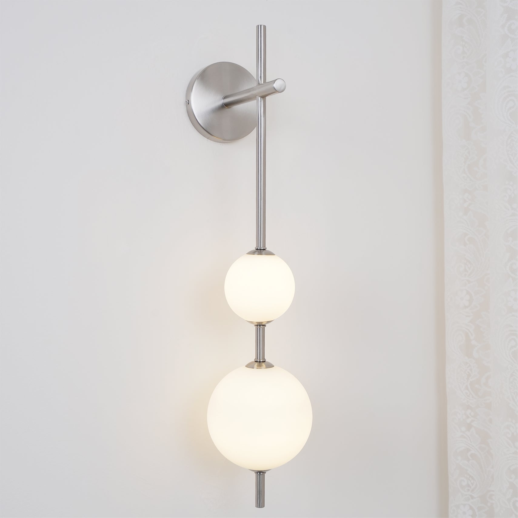 "Elegant vegglampe i glass og messing med kuleformede skjermer for mykt lys, perfekt for moderne og klassiske hjem."