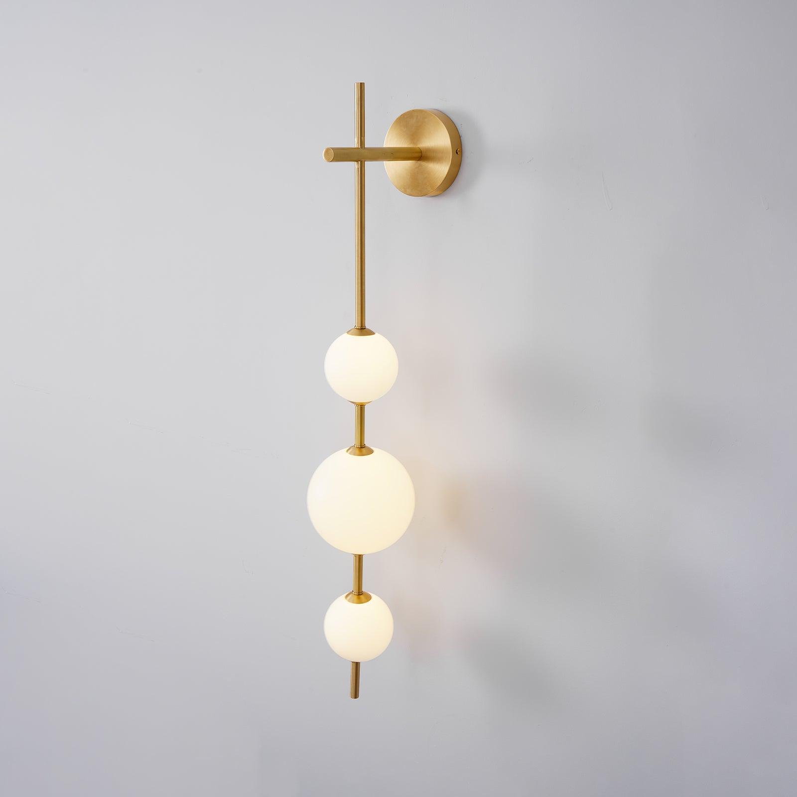 "Elegant vegglampe i glass og messing med kuleformede skjermer for mykt lys, perfekt for moderne og klassiske hjem."