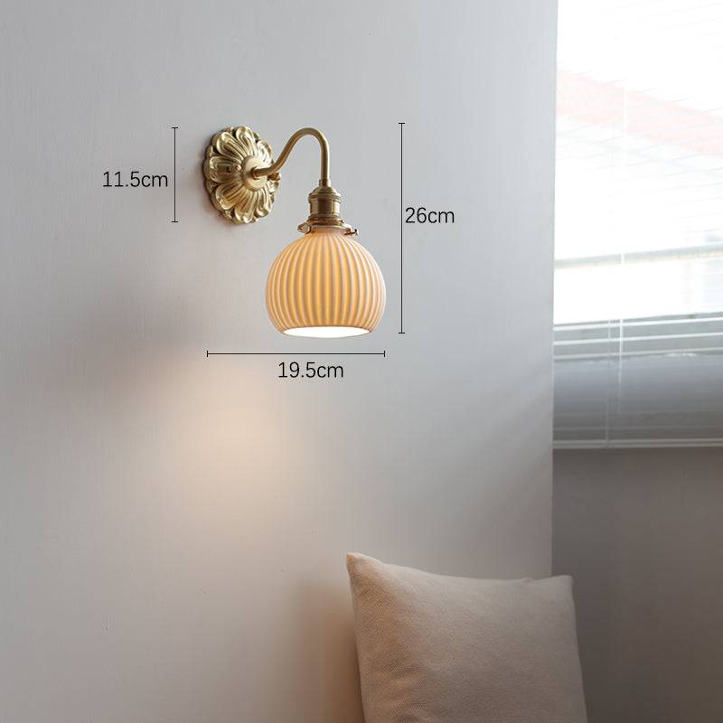 "Elegant vegglampe i messing og keramikk med antikk finish og hvit lampeskjerm, gir klassisk preg til interiøret."