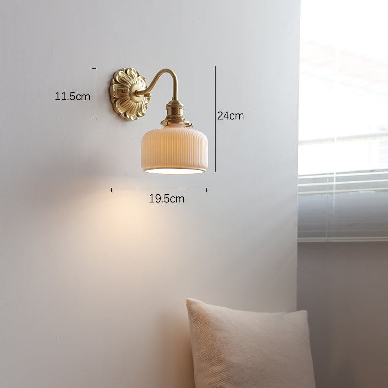 "Elegant vegglampe i messing og keramikk med antikk finish og hvit lampeskjerm, gir klassisk preg til interiøret."