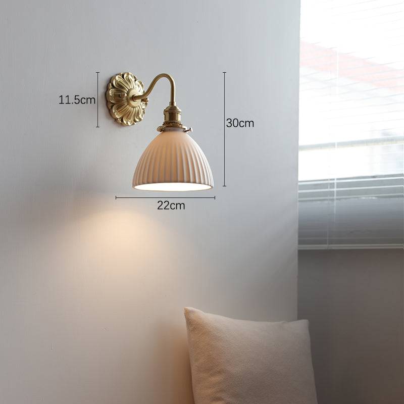 "Elegant vegglampe i messing og keramikk med antikk finish og hvit lampeskjerm, gir klassisk preg til interiøret."
