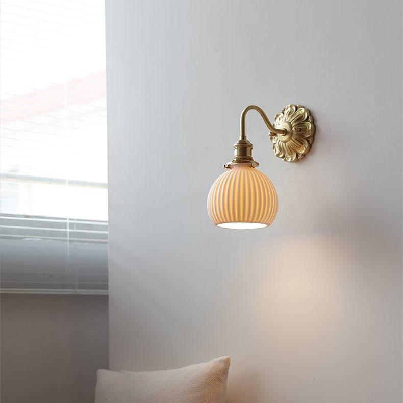 "Elegant vegglampe i messing og keramikk med antikk finish og hvit lampeskjerm, gir klassisk preg til interiøret."