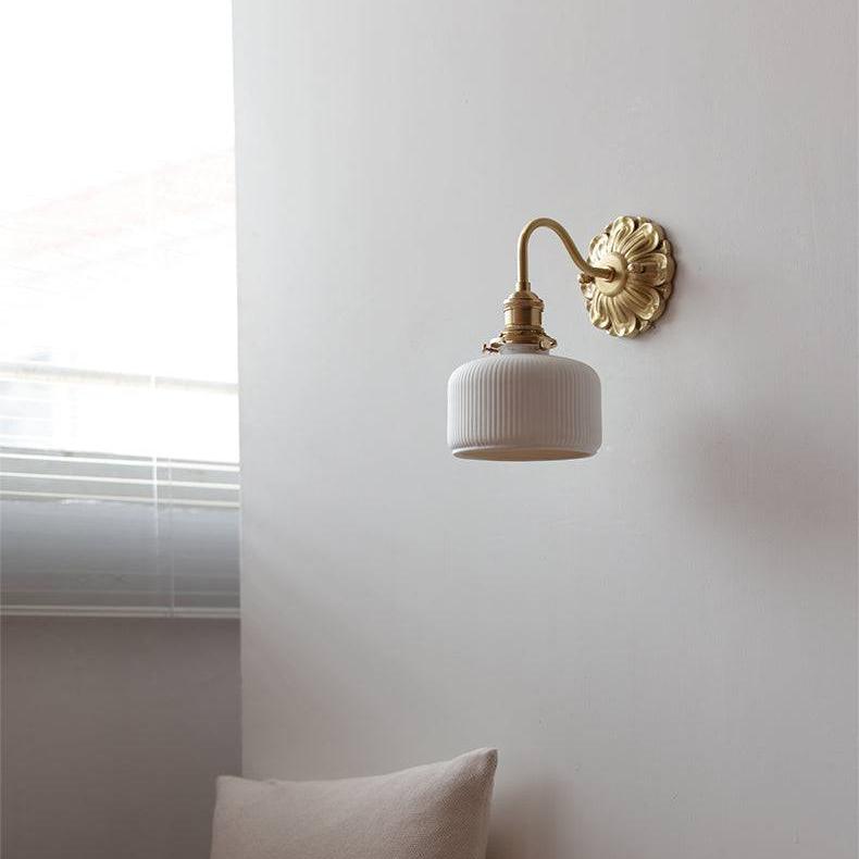 "Elegant vegglampe i messing og keramikk med antikk finish og hvit lampeskjerm, gir klassisk preg til interiøret."