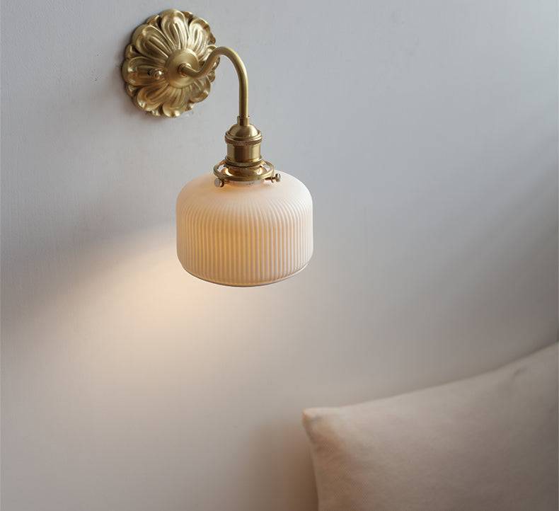 "Elegant vegglampe i messing og keramikk med antikk finish og hvit lampeskjerm, gir klassisk preg til interiøret."