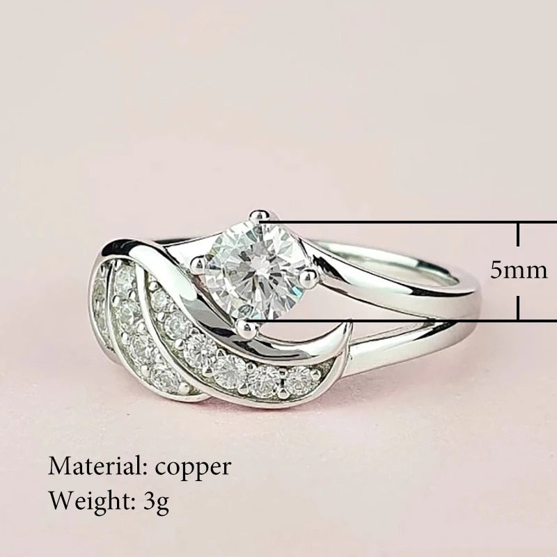 Symbolsk ring: Englens Omfavnelse, laget i sølv med en rekke cubic zirconia for ekstra glans.