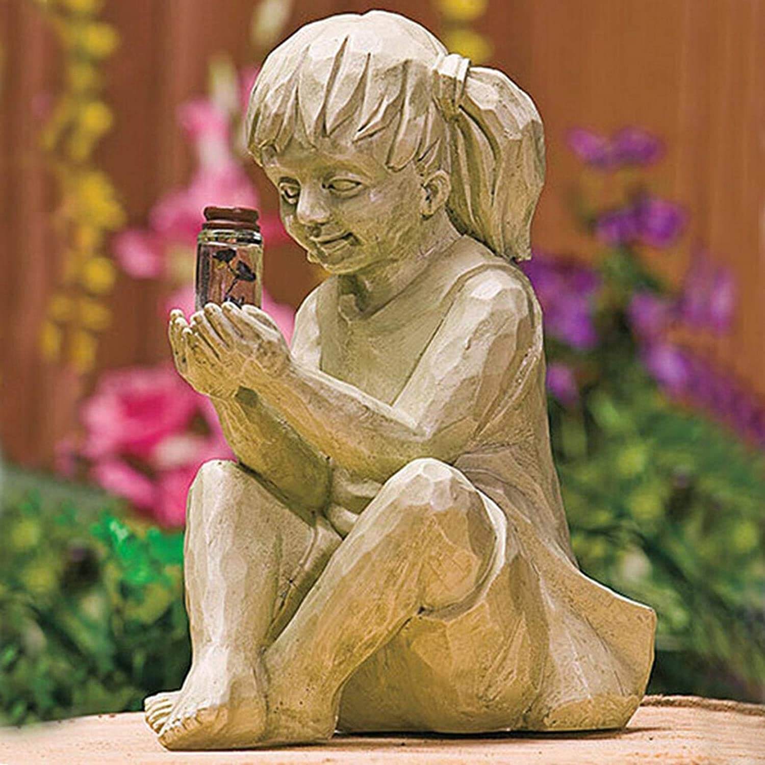 Detaljert hagestatue av jente som holder glødende ildfluer drevet av solcelle.