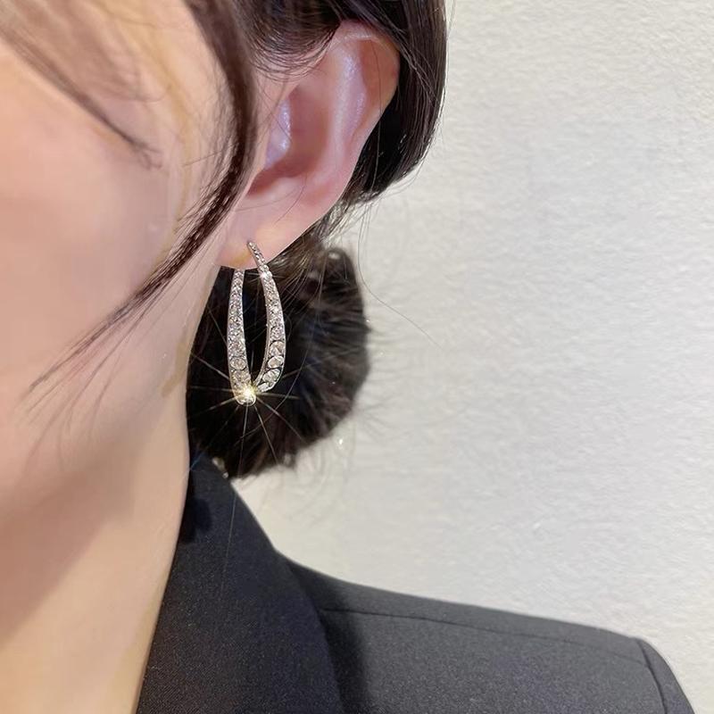 "Kryss buede øredobber i gyllen og sølv med strass, elegante for enhver anledning, allergivennlig materiale."