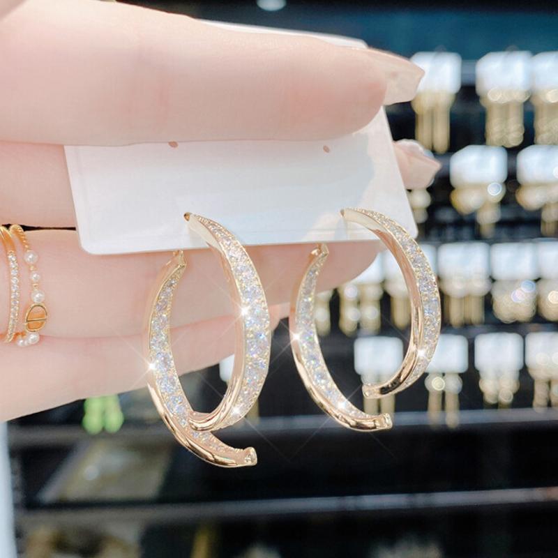 "Kryss buede øredobber i gyllen og sølv med strass, elegante for enhver anledning, allergivennlig materiale."