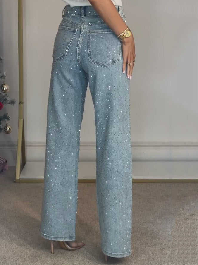 Nærbilde av glitrende detaljer på mørkeblå damejeans med høy midje, fremhever tekstur og design.