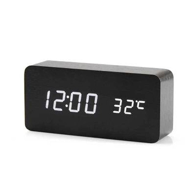 Minimalistisk digital vekkerklokke i fokus, viser tid med hvit LED, bakgrunn utydelig interiør.