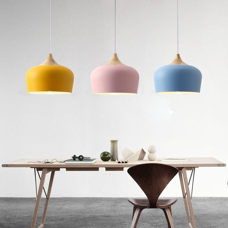 Sett med flere minimalistiske pendellamper i ulike pastellfarger over en kjøkkenøy.