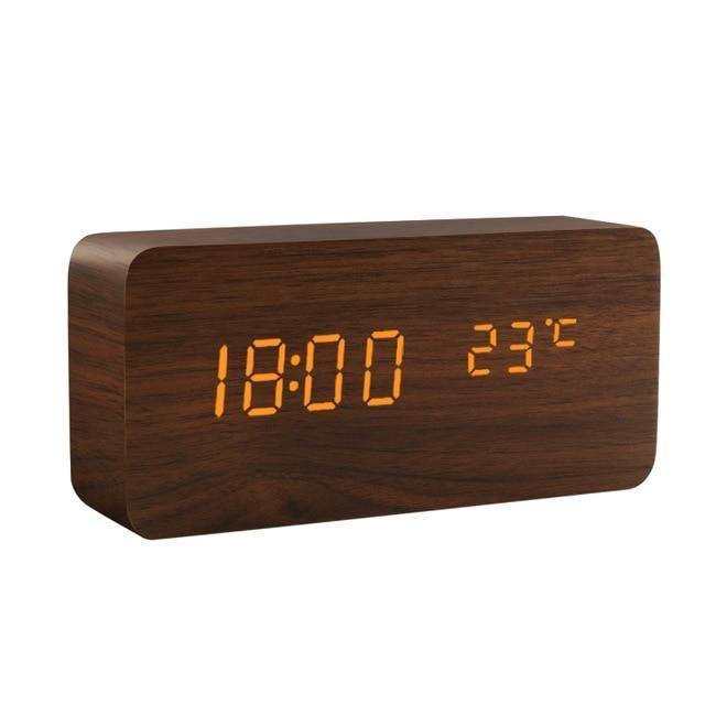 Svart digital vekkerklokke på nattbord, viser tid og har slumrefunksjon, flott for soverommet.