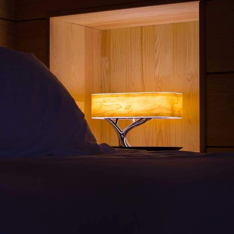 Elegant tre design bordlampe med varmt stemningslys og innebygd Bluetooth-høyttaler.