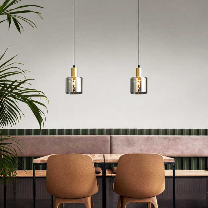 "Pendellampe i svart med gylne detaljer, røykfarget glass; justerbart lys for moderne stil og luksuriøs atmosfære."