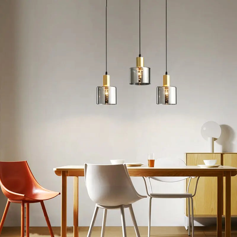 "Pendellampe i svart med gylne detaljer, røykfarget glass; justerbart lys for moderne stil og luksuriøs atmosfære."