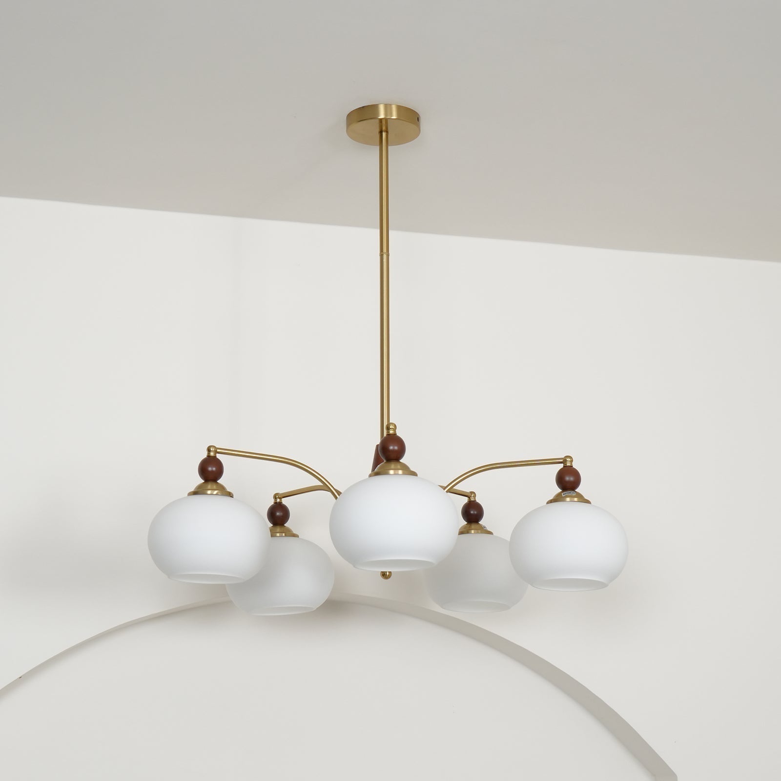 "Retro lysekrone med gyllengule skjermer og klassisk design, laget av tre og messing, gir varmt lys til spisestue."