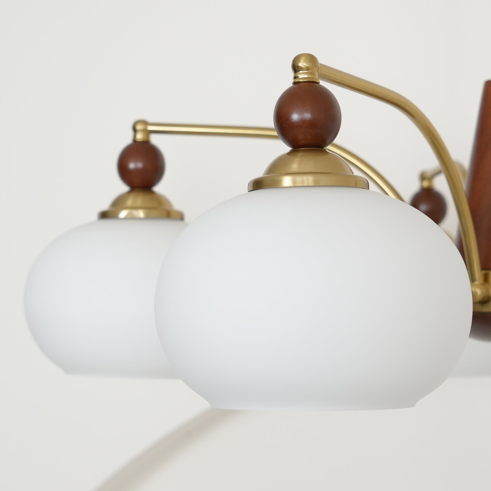 "Retro lysekrone med gyllengule skjermer og klassisk design, laget av tre og messing, gir varmt lys til spisestue."
