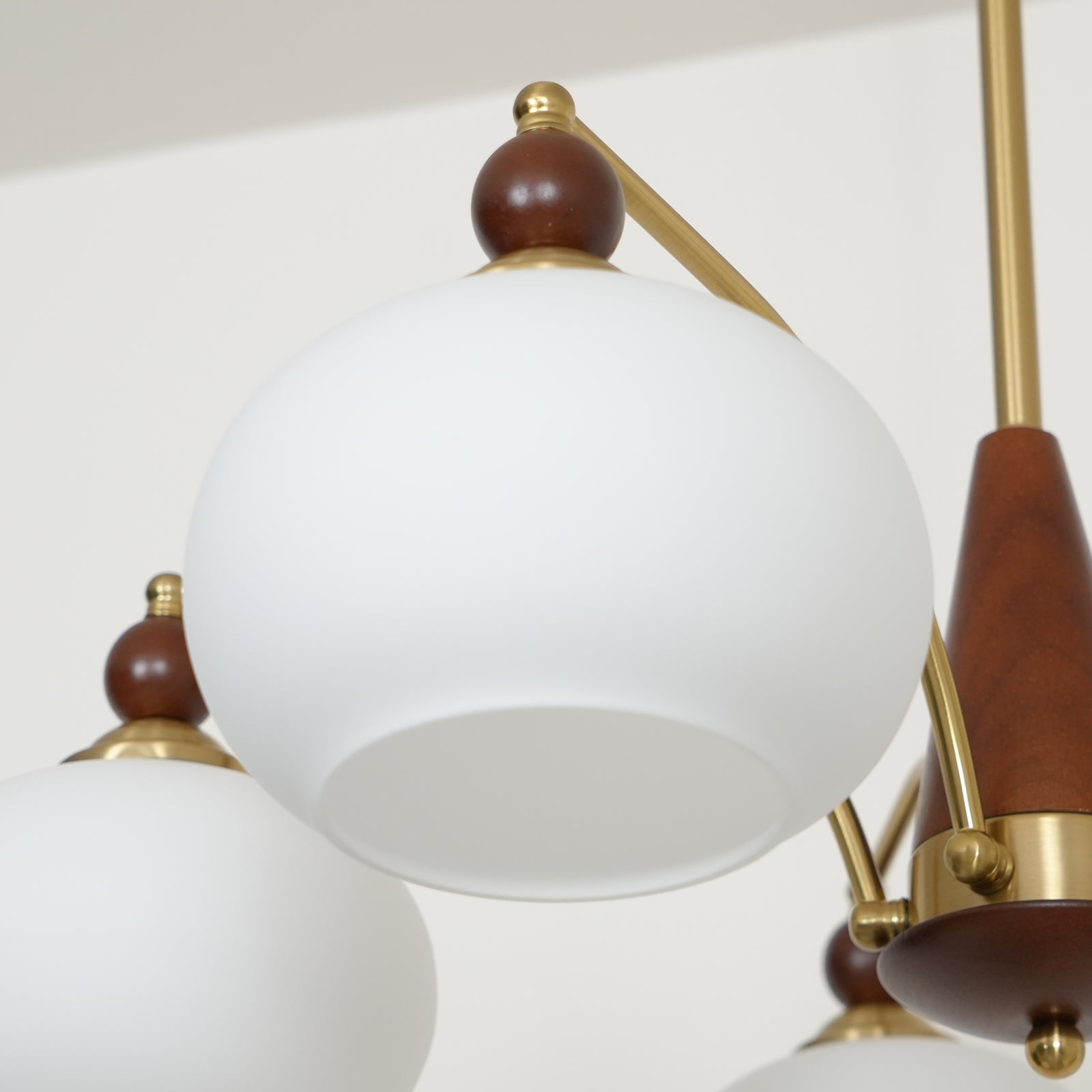 "Retro lysekrone med gyllengule skjermer og klassisk design, laget av tre og messing, gir varmt lys til spisestue."