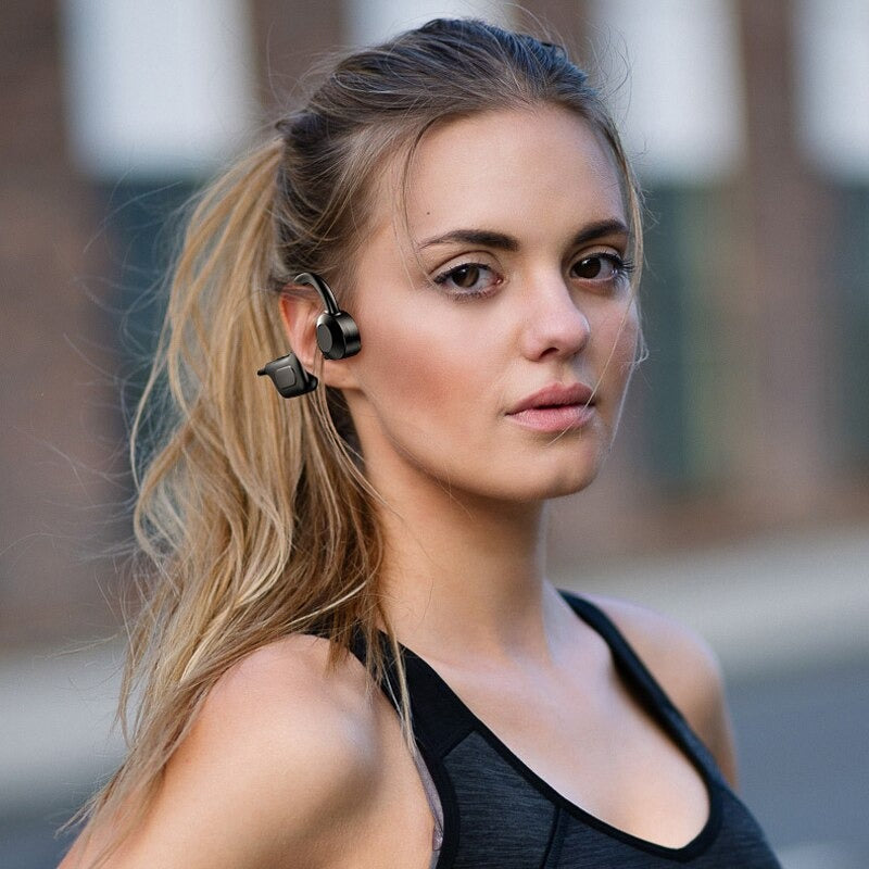 Bluetooth beinledningshodetelefoner på et surfalt brett, fremhever vannmotstand og åpen øre.